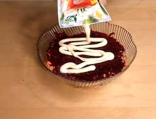 Подготовленную свеклу выкладываем на морковь, щедро смазываем майонезом,